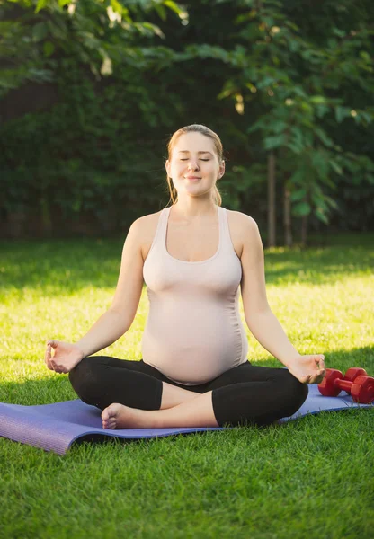 Vackra gravid kvinna avkopplande och mediterar utomhus — Stockfoto