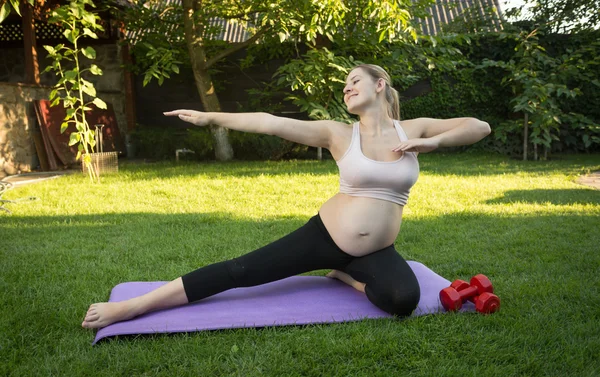 Kobieta w ciąży rozciąganie w parku w słoneczny dzień — Zdjęcie stockowe