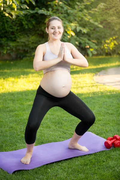 Donna incinta che fa yoga sull'erba al parco — Foto Stock