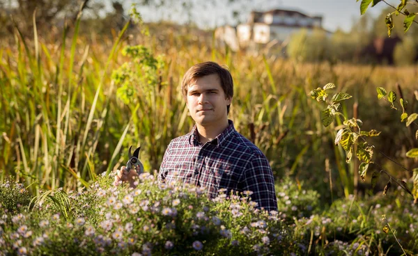 Retrato del hombre trabajando en el jardín y cortando flores — Foto de Stock