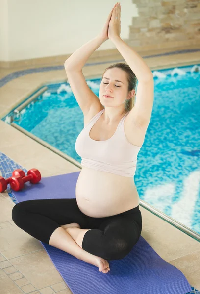 Donna incinta che fa yoga sul lato della piscina — Foto Stock
