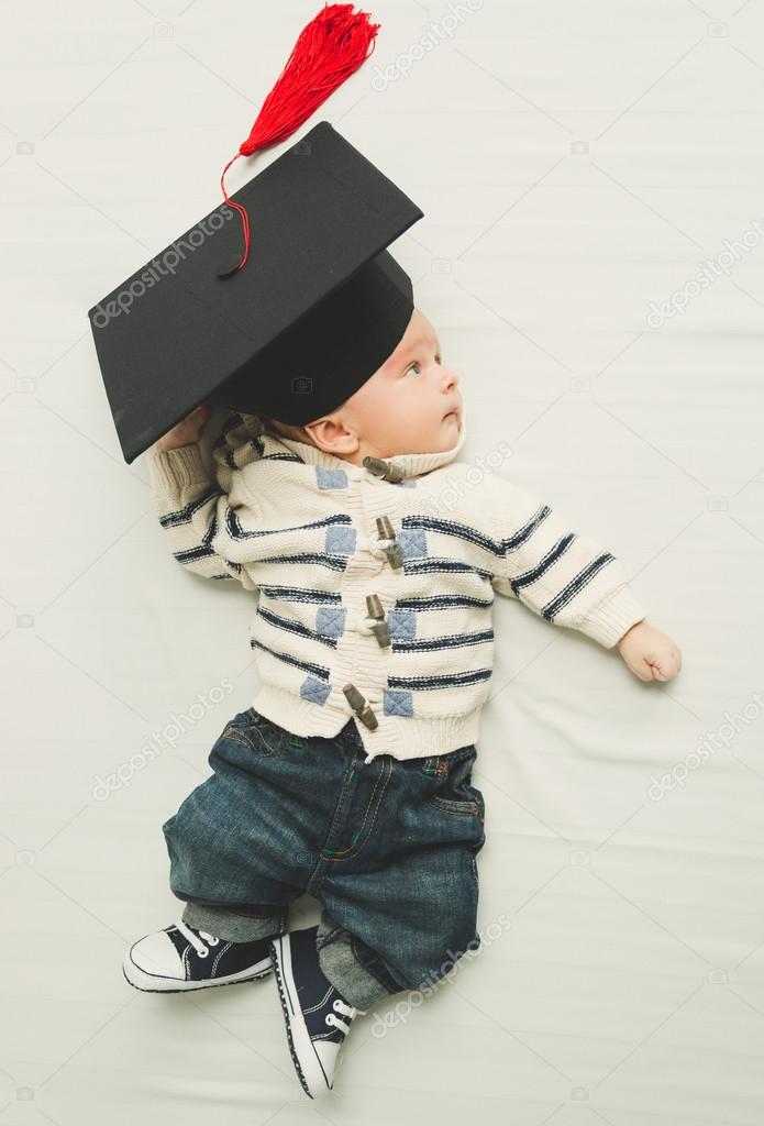 portrait of cute baby boy posing in black graduation cap
