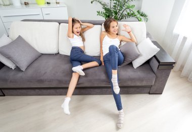 İki kız oturma odasında kanepede eğleniyor