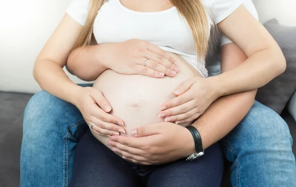 Pregnant couple holding hands on big belly — Stock Photo, Image