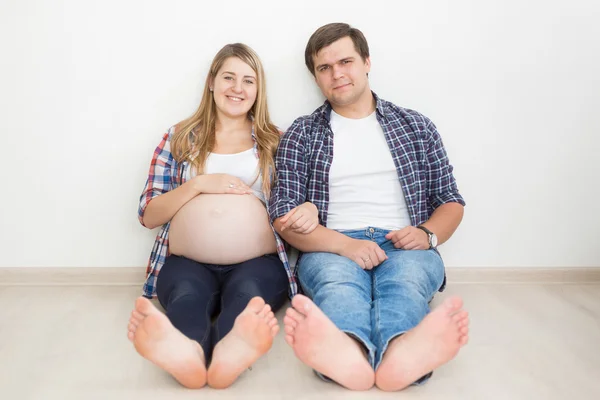 Glad gravid kvinna sitter på golvet med make — Stockfoto