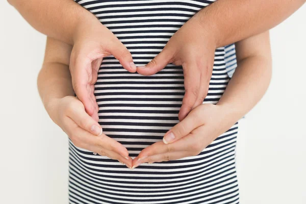 Toned photo of pregnant woman and husband holding hands in shape — Stock Photo, Image