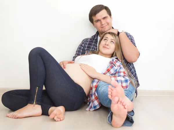 Jovem casal esperando bebê posando no chão na sala de estar — Fotografia de Stock