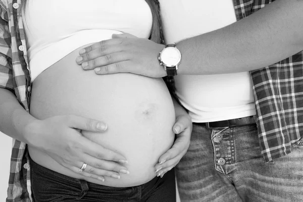 妊娠中の妻のおなかに触れる若い父親の黒と白の写真 — ストック写真