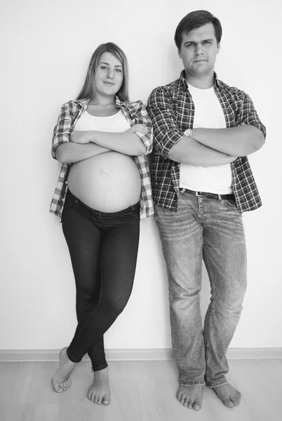 Genç hamile çift boş oda beyaz duvara yaslanmış — Stok fotoğraf