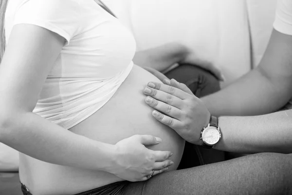 Black and white photo of man holding hands on pregnant wife bell — Stock Photo, Image