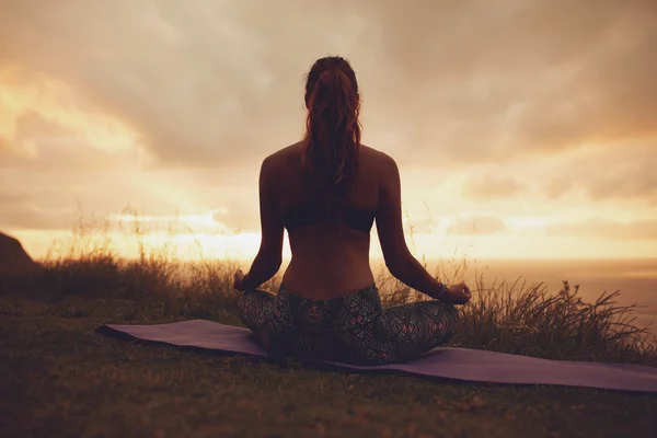 Mulher em pose de ioga de lótus durante o pôr do sol — Fotografia de Stock