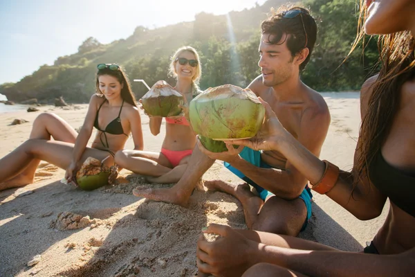 Amigos disfrutando de vacaciones en la playa con cocos — Foto de Stock