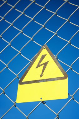 Elektriksel tehlike işareti metal bir çite yerleştirilmiş..