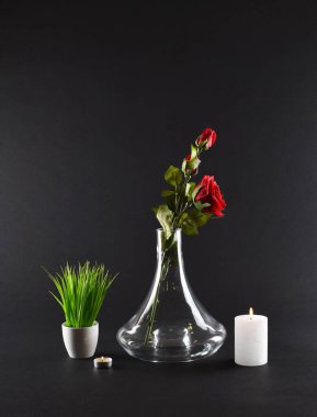 Yeşil çimen ve mumlarla siyah arkaplanlı şeffaf cam şişe.