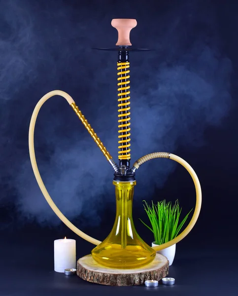 yellow hookah with smoke on a black background with candles