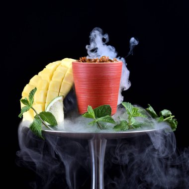 Siyah arka planda tütünlü nargile kasesi, mango, kireç, nane