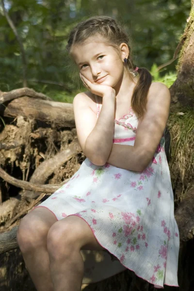 Mädchen sitzt im Holz — Stockfoto