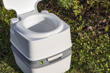 Sokak lambası. Ön planda taşınabilir plastik bir tuvalet. Arkada bir ağaç var.
