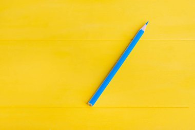 Stüdyo ışıkları. Ahşap arka plan sarıya boyanmış. Mavi bir kalem..