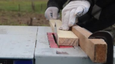 Gün ışığı. Tahta testeresi makinesi. Usta tahtayı verir. Yakın plan..