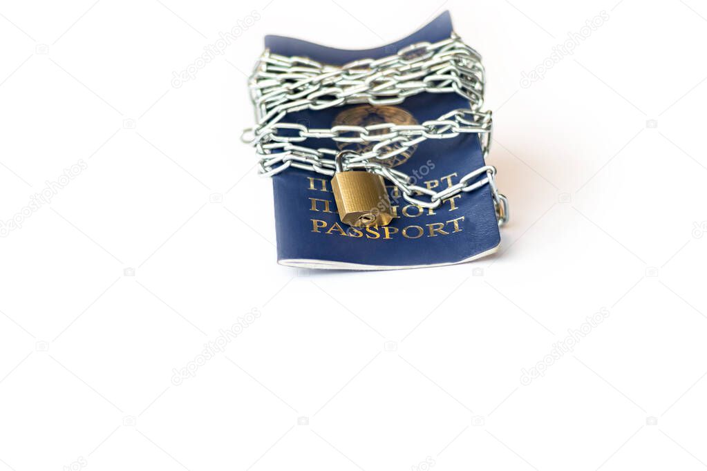 Studio lighting. the citizen's passport is tied with a metal chain in the center with a yellow lock. The concept of violation of the rights of citizens, a ban on movement.