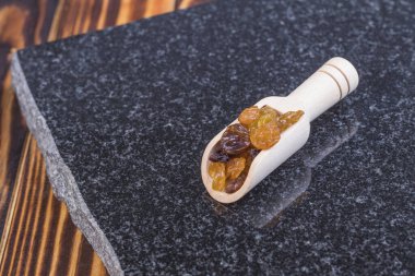 Stüdyo ışıkları. Eski usul ahşap arka plan, antika. Baharatlar için bir kaşık var, içinde birkaç kuru üzüm var..