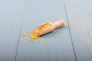 Stüdyo ışıkları. Tahta bir arka planda darı, tahta bir kaşık, arka plan karanlık. Bir gölge var. Yakın plan..