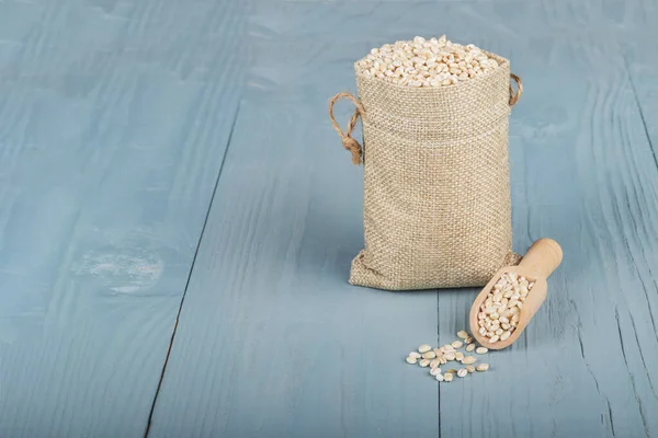 Retro tarzı ahşap arka plan. Üzerinde küçük bir torba var, arpa. Mesajın için yer aç. Boşluğu kopyala