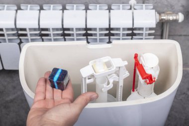 Stüdyo ışıkları. Banyo. Klozet. Ev hanımı varillere özel temizlik ve dezenfeksiyon maddesi ekliyor.