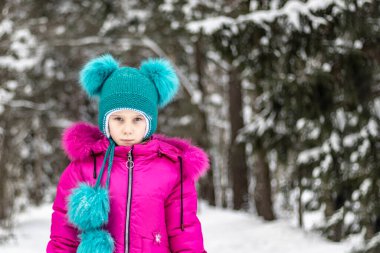 Doğal ışık. Kırmızı ceketli ve yeşil şapkalı bir kız çok fazla karla çevrili. O bize bakıyor. Yumuşak odak