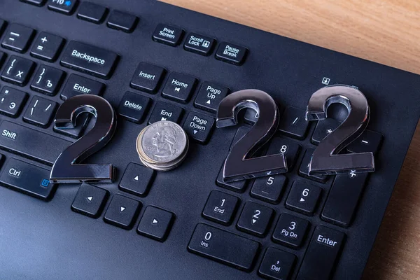 black keyboard close-up. on it are laid out numbers of metal 2022 in the center of the coin 0.25 dallar