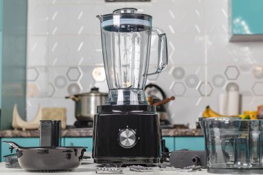 Doğal ışık. Siyah gıda işlemcisi. Kullanmak için başlığın yanında. Arka planda yemek yapmak için bir mutfak var.