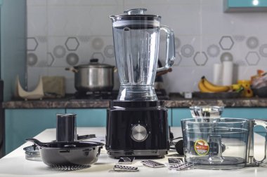 Doğal ışık. Siyah gıda işlemcisi. Kullanmak için başlığın yanında. Arka planda yemek yapmak için bir mutfak var.