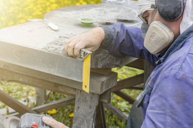 Sokak lambası. Maskeli bir işçi granit taşı özel bir aletle işliyor. Yakın plan.