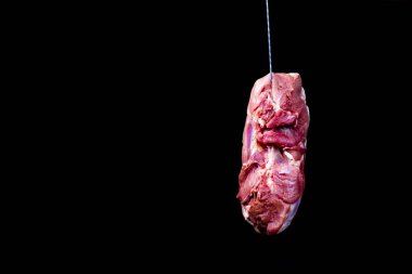 Stüdyo ışıkları. Karanlık arka plan. Bir parça et kancaya asılmış. Yakın plan..