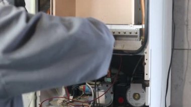 Usta duvara asılı bir gaz kazanı kuruyor. Ön torpido gözü açık. Isıtma ayarlandı ve başladı..