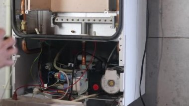 Usta duvara asılı bir gaz kazanı kuruyor. Ön torpido gözü açık. Isıtma ayarlandı ve başladı..
