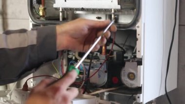 Usta duvara asılı bir gaz kazanı kuruyor. Ön torpido gözü açık. Isıtma ayarlandı ve başladı..
