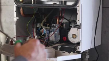 Usta duvara asılı bir gaz kazanı kuruyor. Ön torpido gözü açık. Isıtma ayarlandı ve başladı..