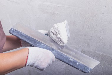 Stüdyo ışıkları. Metal bir spatula ustası çözeltiyi dengelemek için duvara uyguluyor. Yakın plan..
