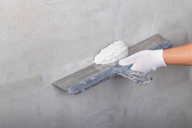 Stüdyo ışıkları. Metal bir spatula ustası çözeltiyi dengelemek için duvara uyguluyor. Yakın plan..