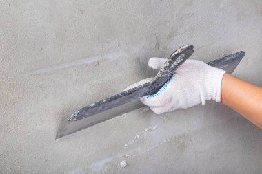 Stüdyo ışıkları. Metal bir spatula ustası çözeltiyi dengelemek için duvara uyguluyor. Yakın plan..