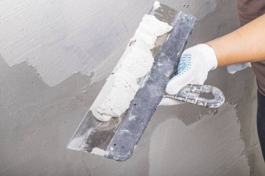 Stüdyo ışıkları. Metal bir spatula ustası çözeltiyi dengelemek için duvara uyguluyor. Yakın plan..