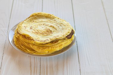 Geçmişe dönük beyaz ahşap arka plan. Tabaktaki ince sarı krep. yakın plan