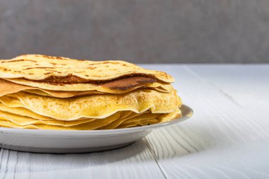 Geçmişe dönük beyaz ahşap arka plan. Tabaktaki ince sarı krep. yakın plan