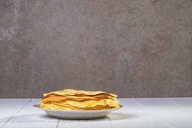 Geçmişe dönük beyaz ahşap arka plan. Tabaktaki ince sarı krep. yakın plan