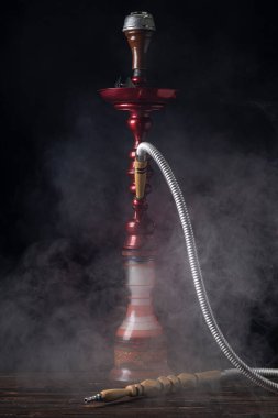 Yakın plan. Cam mataralı nargile ve metal kaseli nargile dumanı var. Siyah arka plan. Ön görünüm