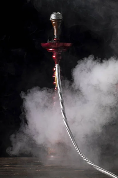 close-up. Hookah with a glass flask and a metal bowl hookah, there is a smoke of smoke. Black background. Front view