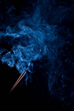 Siyah arka plan, iki tütsü çubuğu. Duman, koku, tütsü var.