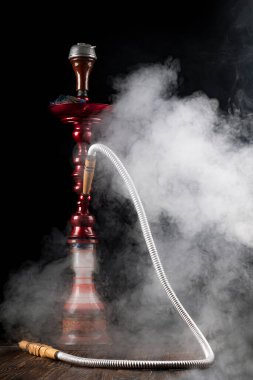 Yakın plan. Cam mataralı nargile ve metal kaseli nargile dumanı var. Siyah arka plan. Ön görünüm